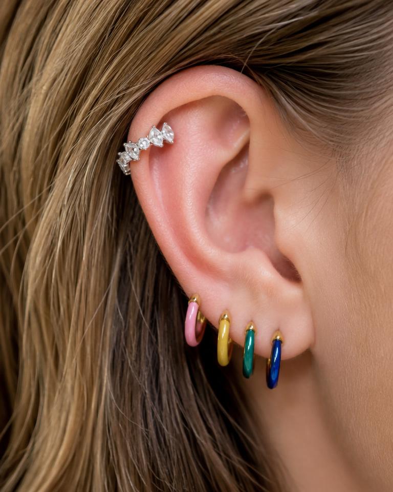 Ear stack of colorful huggie hoops and a crystal ear cuff