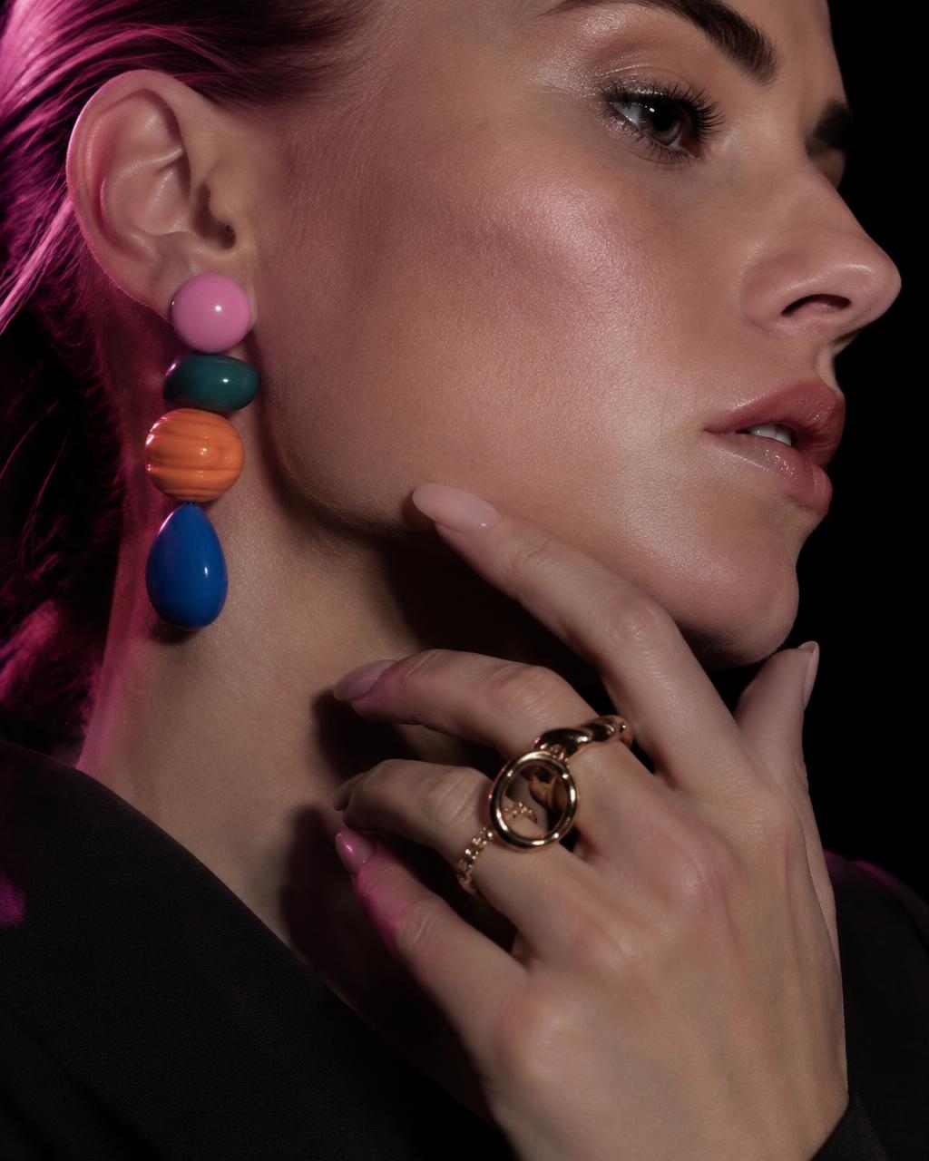 Woman wearing colorful stacked bead earrings and a gold ring